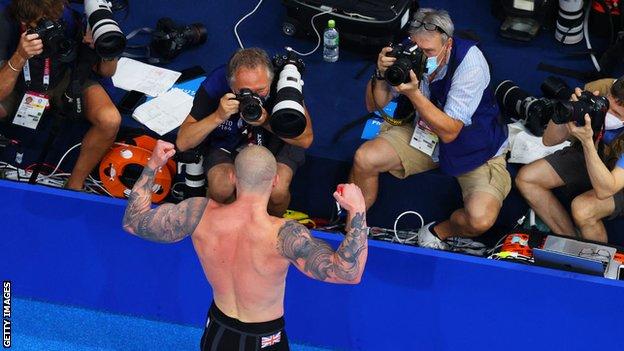 Adam Peaty poses in front of photographers after his gold medal-winning swim