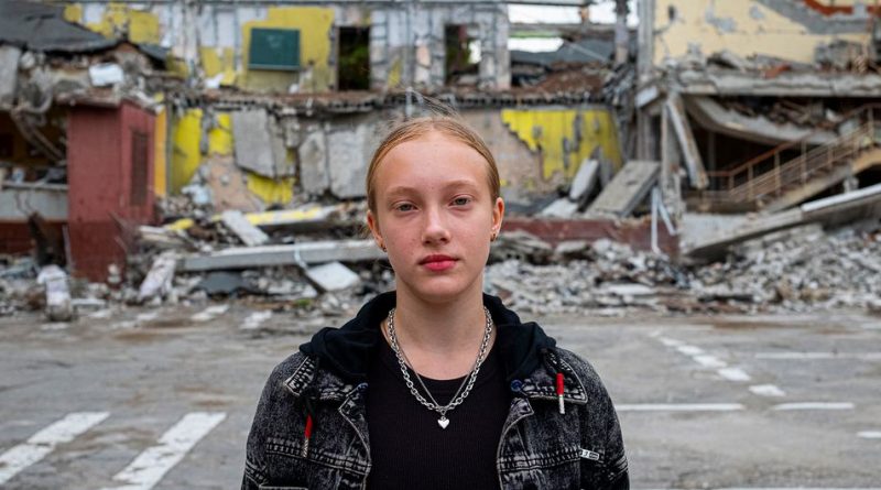 A twelve-year-old girl stands in front of her school which was destroyed in an air strike during the conflict in Kharkiv, Ukraine.