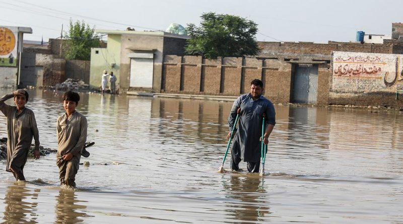 Young boys and a man using crutches pass through the flooded streets of Nowshera Kalan, one of the worst affected area in Khyber Pakhtunkhwa province, Pakistan.