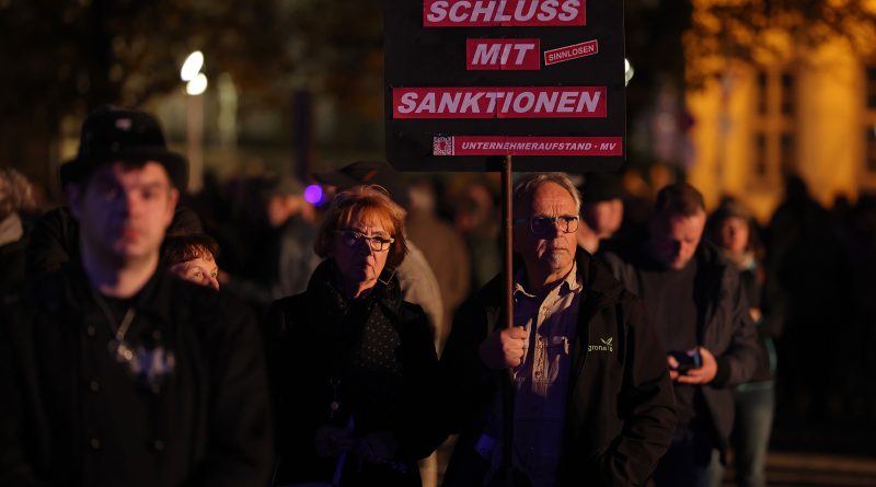A man holds a sign that reads: "Enough with sanctions" prior to a Monday-night "stroll" ("Spaziergang") of protesters on Oct. 24 in Schwerin, Germany. (Sean Gallup—Getty Images)