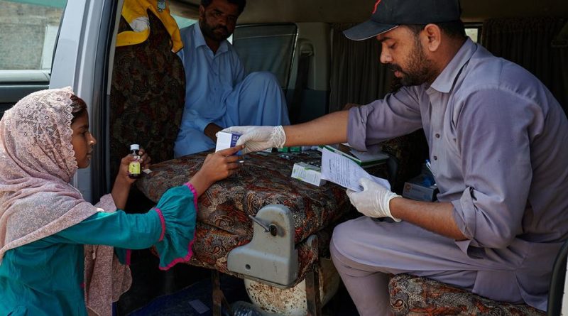 A young girl collects her medication from a mobile health unit set up for flood victims in Shangar District, Pakistan.