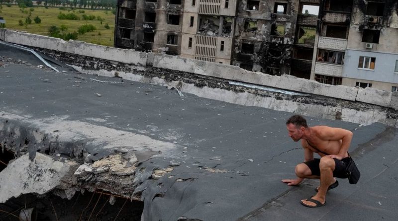 A man inspects damage on the roof of an apartment complex destroyed by artillery and air strikes in a Kharkiv suburb..