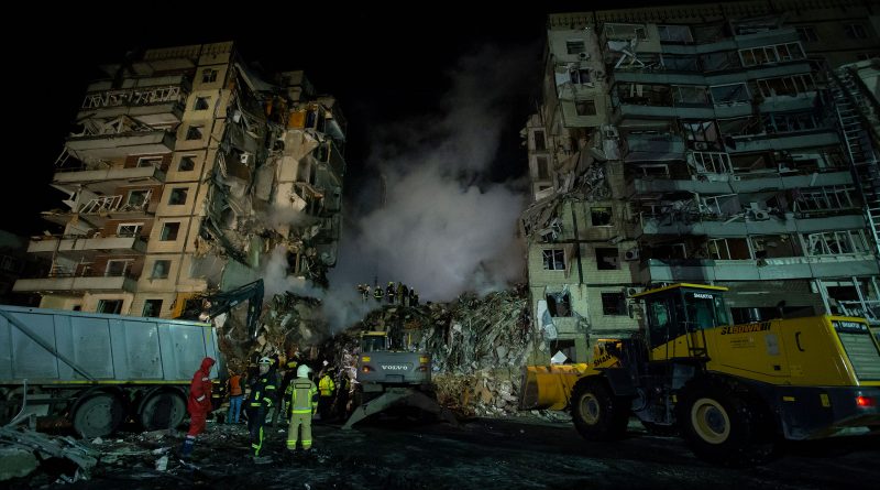 Firefighters stand near a dump truck while their colleagues are conducting search and rescue operations at a residential building hit by a missile in Dnipro, Ukraine on Jan. 15, 2023. (Yan Dobronosov—Global Images Ukraine/Getty Images)