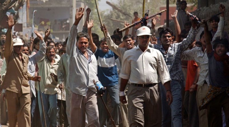 401733 09: A mob of Hindus wielding swords and sticks back off after Indian Rapid Reaction Force officers stopped them from attacking a small group of Muslims March 1, 2002 in Ahmadabad, India. (Ami Vitale—Getty Images)