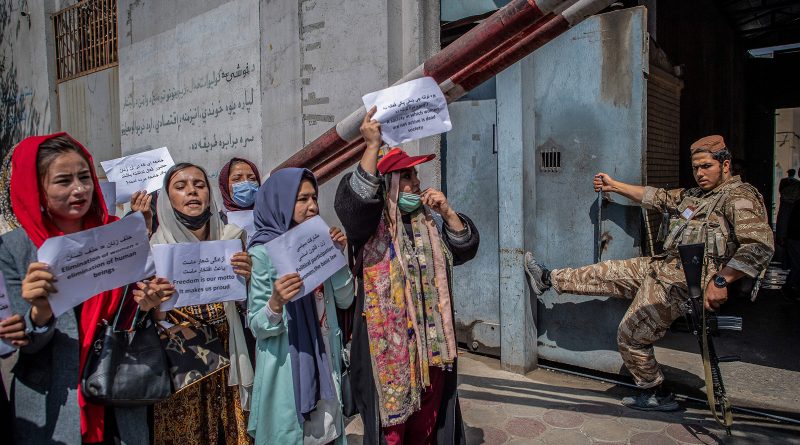 A Taliban fighter watches as Afghan women hold placards during a demonstration demanding better rights for women in front of the former Ministry of Women Affairs in Kabul on Sept. 19, 2021. (Bulent Kilic—AFP/Getty Images)